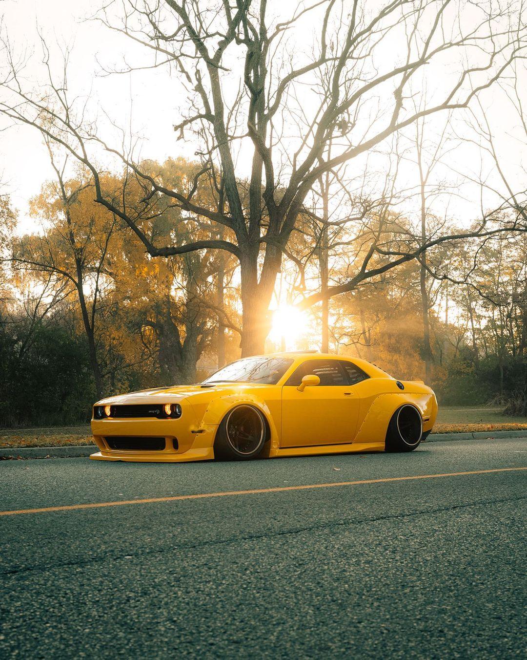 Yellow Dodge Challenger equipped with Dodge Challenger HELLCAT SHIROKAI widebody kit parked on road at sunset