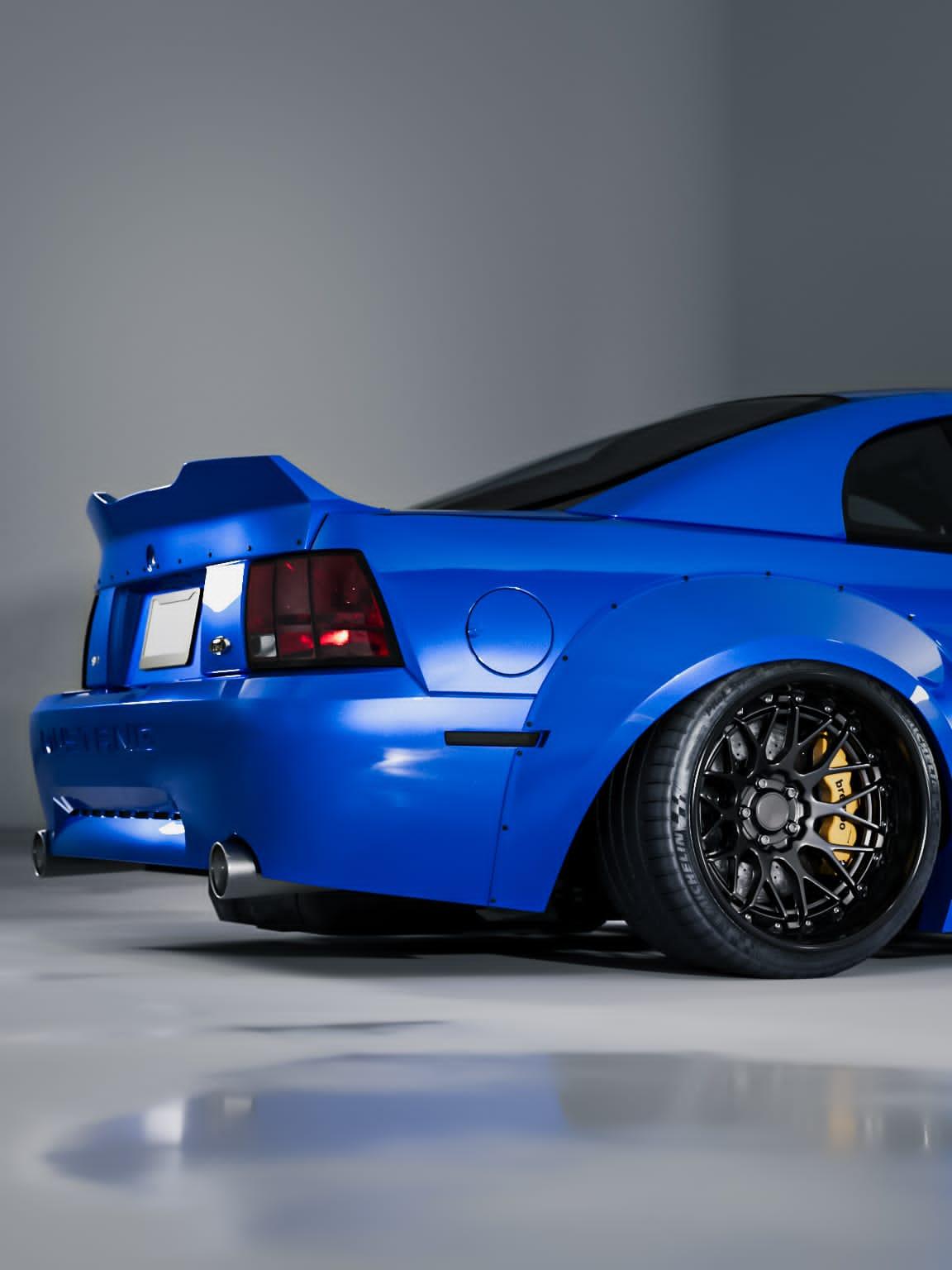 Blue 1999-2004 Mustang SN95 Cobra wide-body kit by SHIROKAI on rear side of car with black wheels