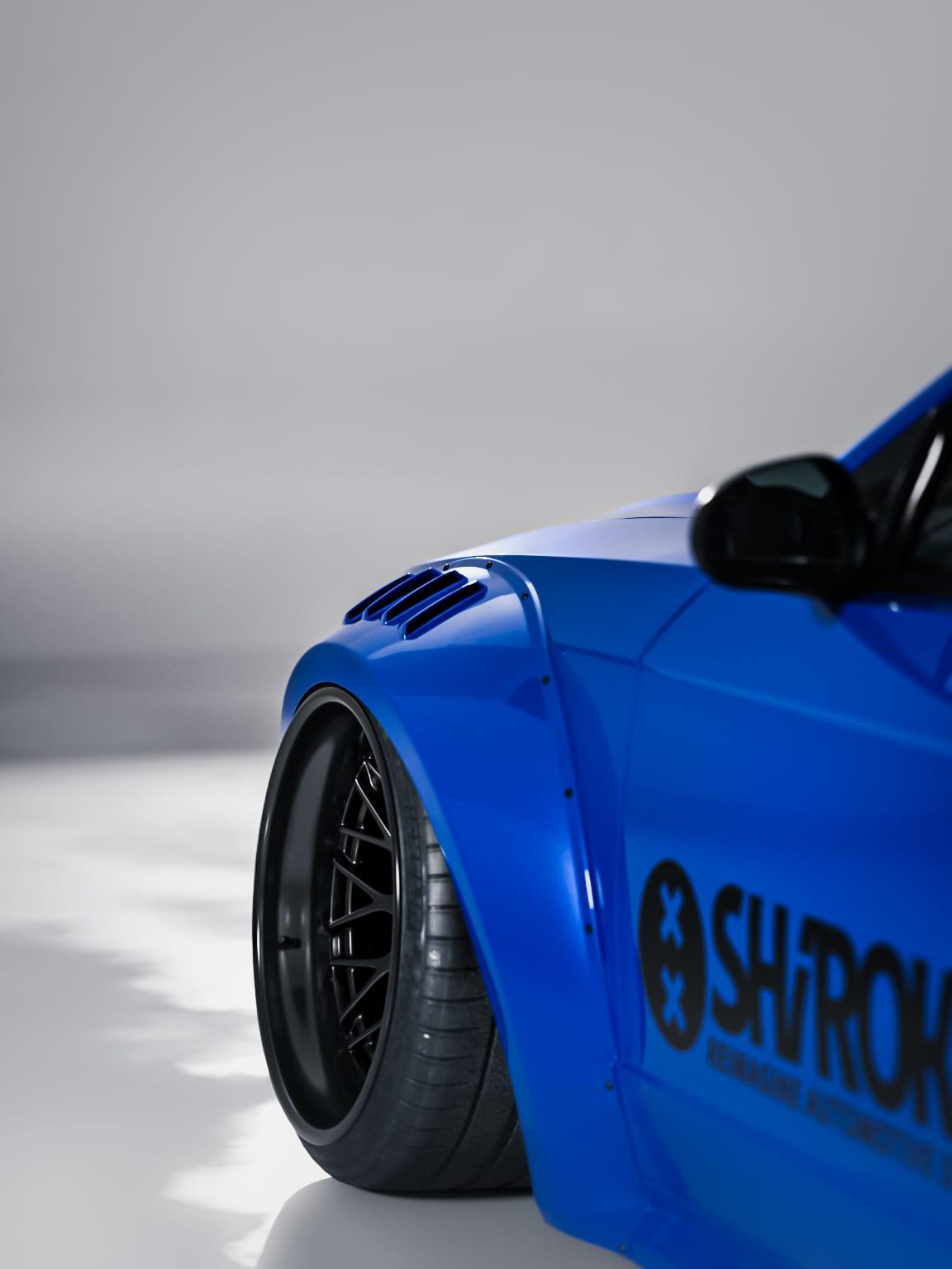 Blue 1999-2004 Mustang SN95 Cobra wide-body kit by SHIROKAI installed on front fender with black wheel