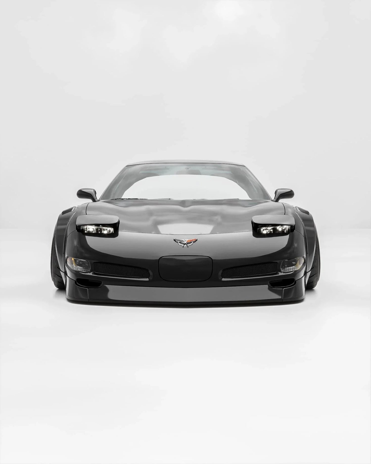 Front view of sleek black Chevrolet Corvette sports car with pop-up headlights on white background