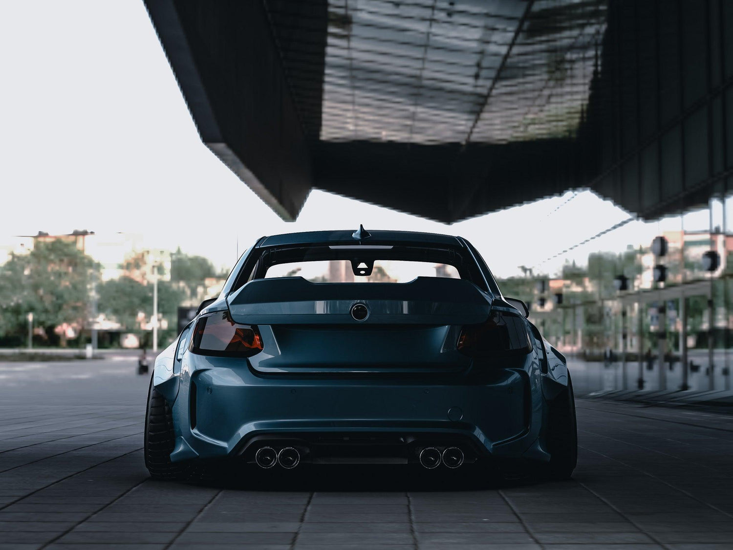 Rear view of a blue BMW M2 2015-2018 widebody kit SHIROKAI installed under urban bridge setting