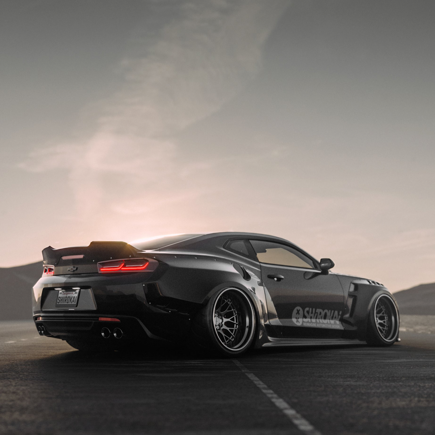 Black Chevrolet Camaro 6th gen widebody kit SHIROKAI Stance lowered Chevy parked on road at sunset