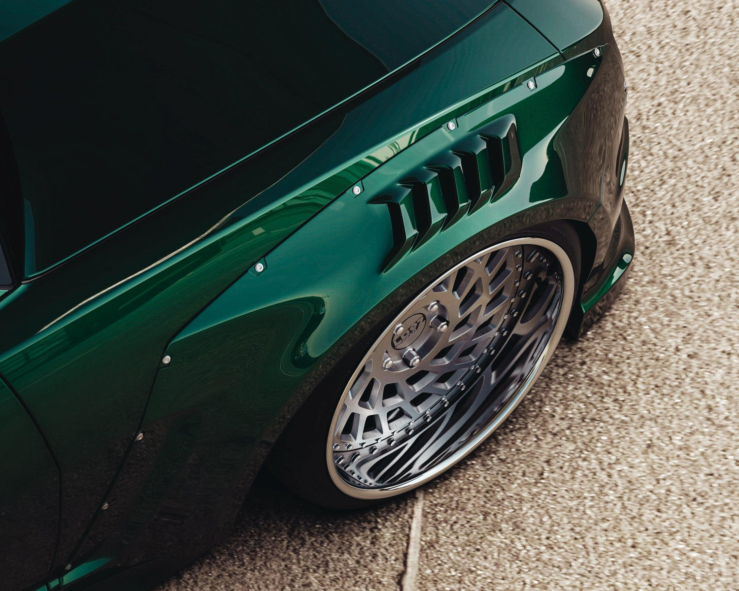 Close-up of a Chevrolet Camaro SS 2010-2013 widebody kit SHIIROKAI overfenders on a dark green car with custom wheels