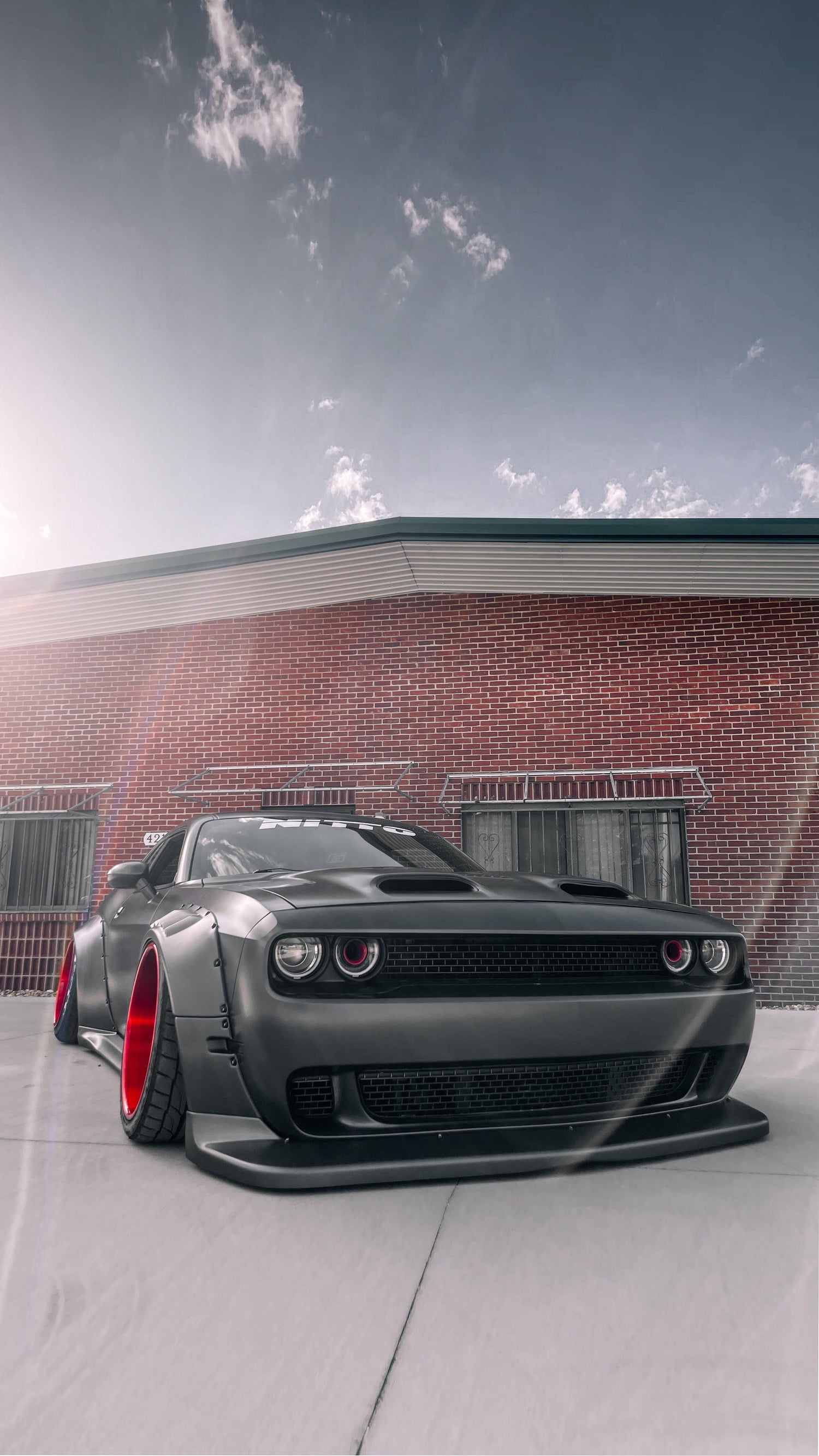 Dodge Challenger HELLCAT SHIROKAI widebody kit on matte black car with red rims and aggressive front splitter