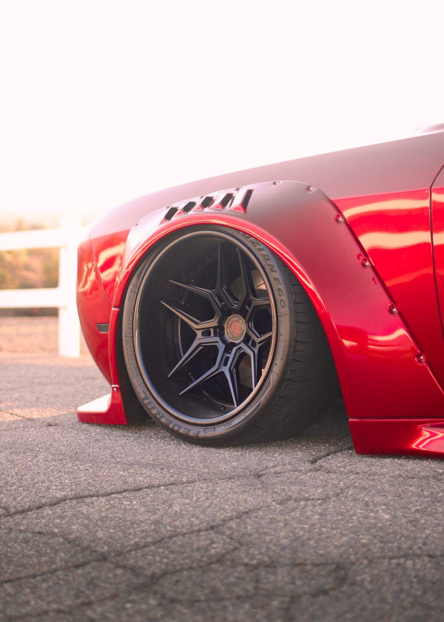 Close-up of a red Dodge Challenger with HELLCAT SHIROKAI widebody kit and custom black wheel