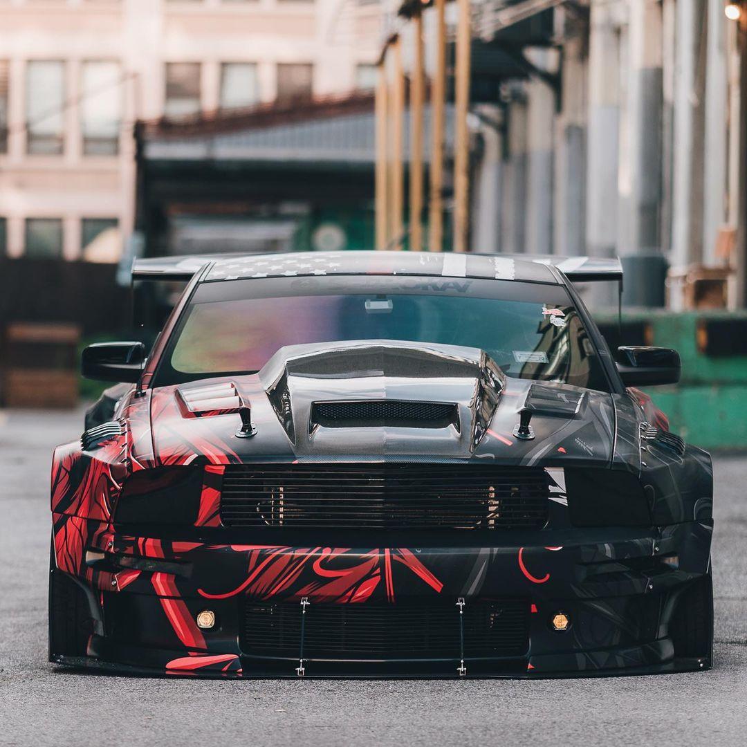 Ford Mustang S197 widebody kit SHIROKAI installed on a custom black and red sports car front view