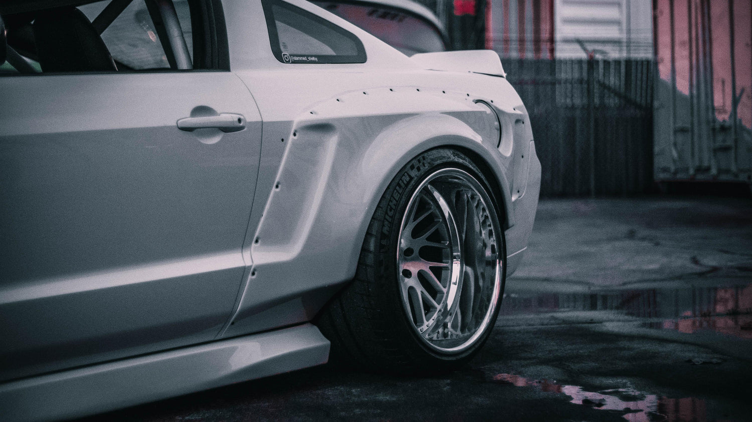 Close-up of a white Ford Mustang with an installed ford mustang S197 widebody kit SHIROKAI showing the rear fender and wheel