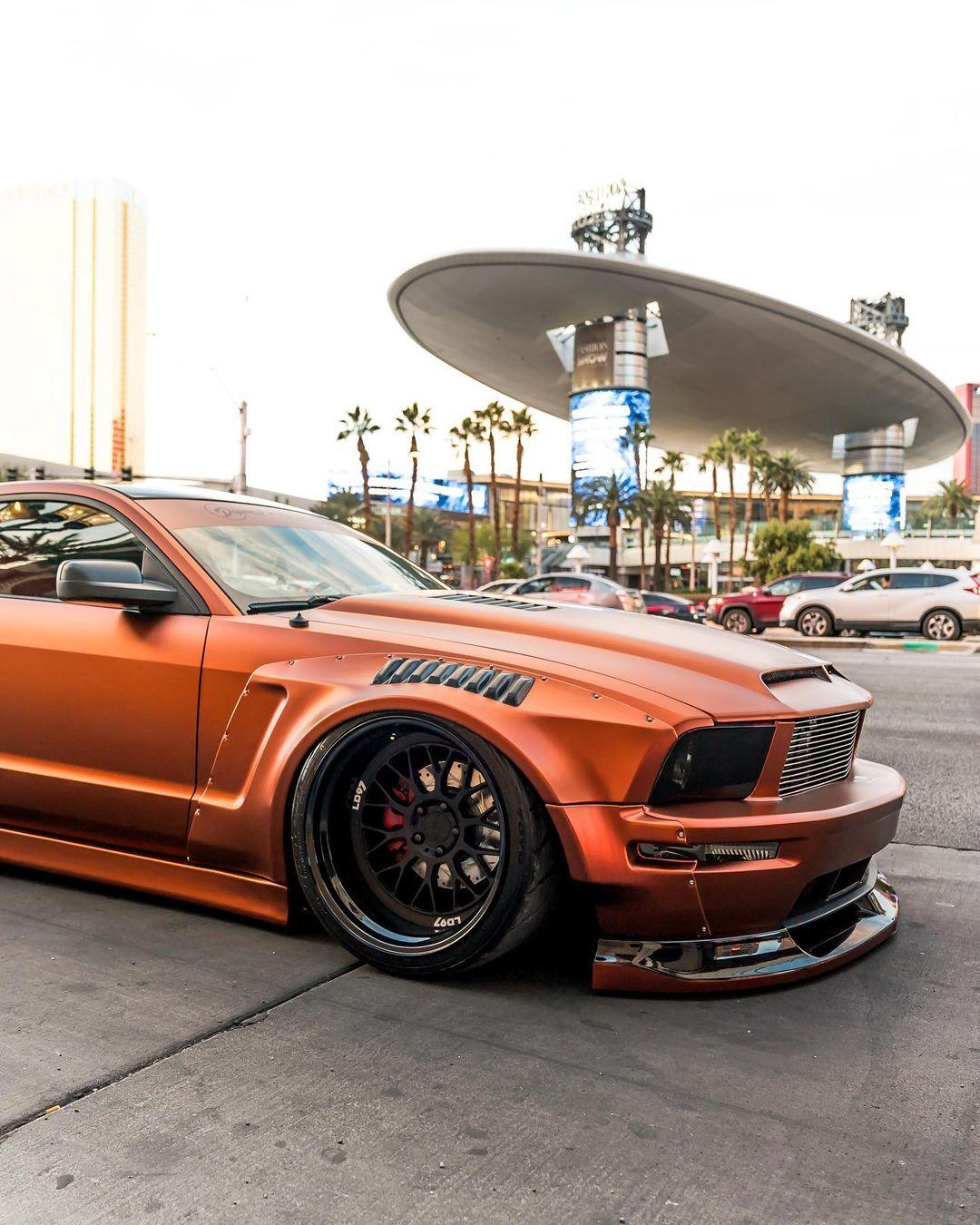 Orange Ford Mustang with ford mustang S197 widebody kit SHIROKAI installed, showing aggressive front and side profile