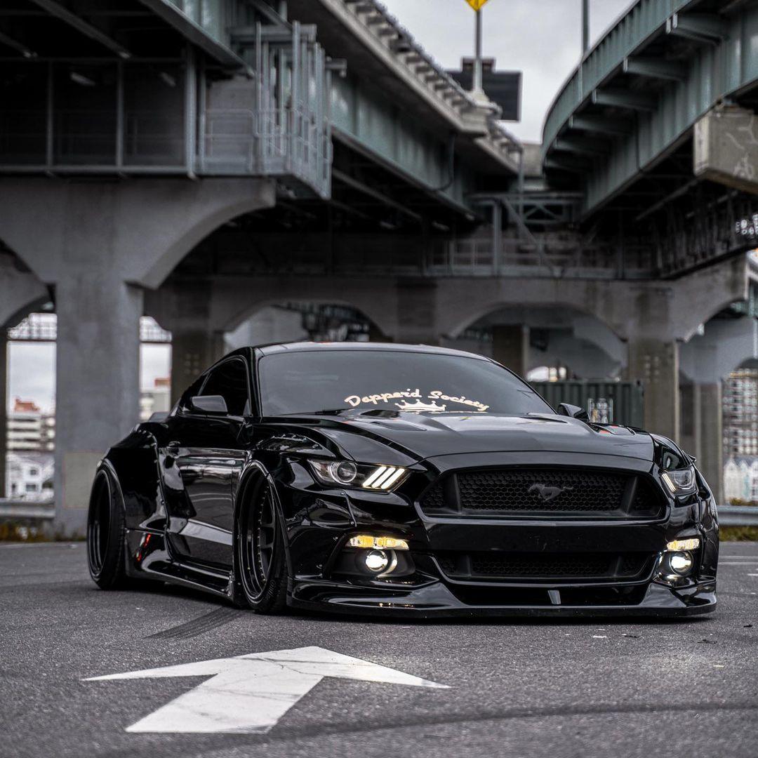 Black Ford Mustang S550 with SHIROKAI widebody kit parked under overpass with aggressive front view