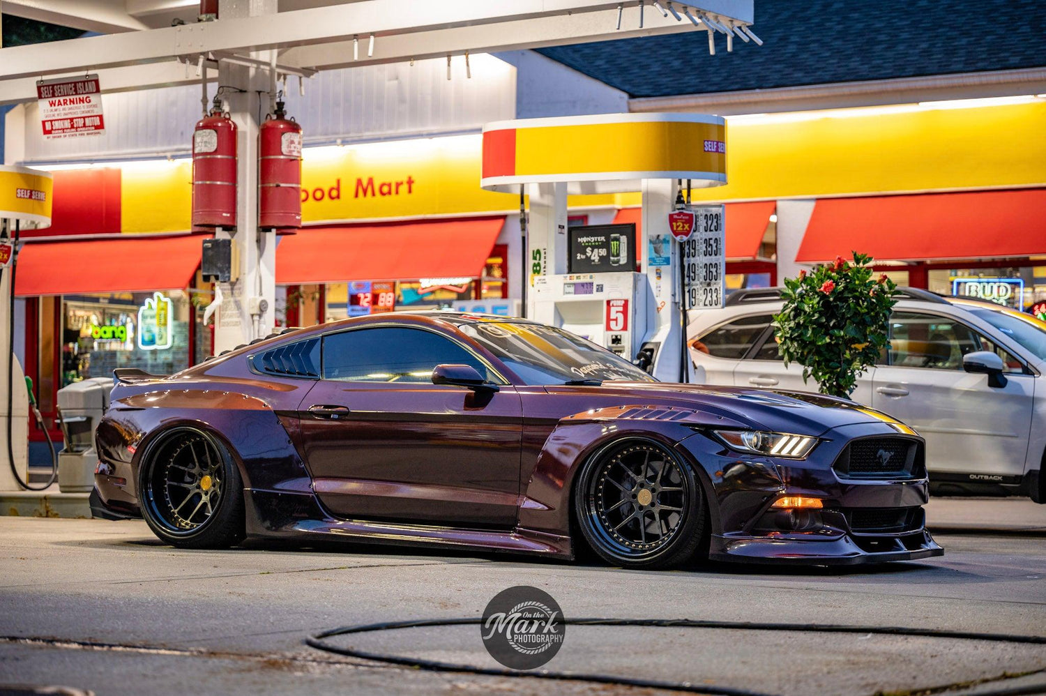 Ford Mustang S550 widebody kit SHIROKAI installed on a dark purple Mustang parked at a gas station