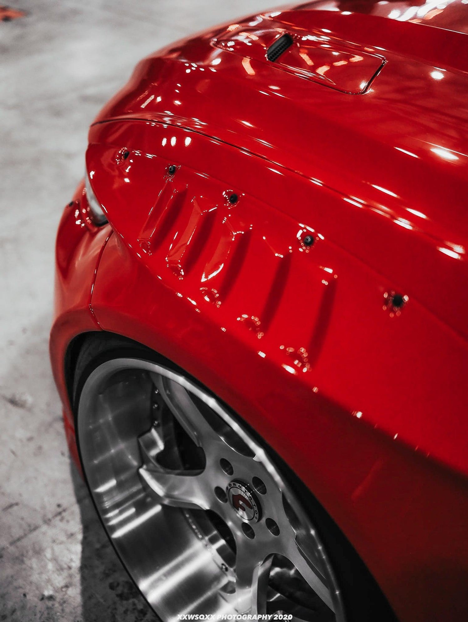 Close-up of red Ford Mustang S550 widebody kit SHIROKAI showing riveted fender and custom wheel