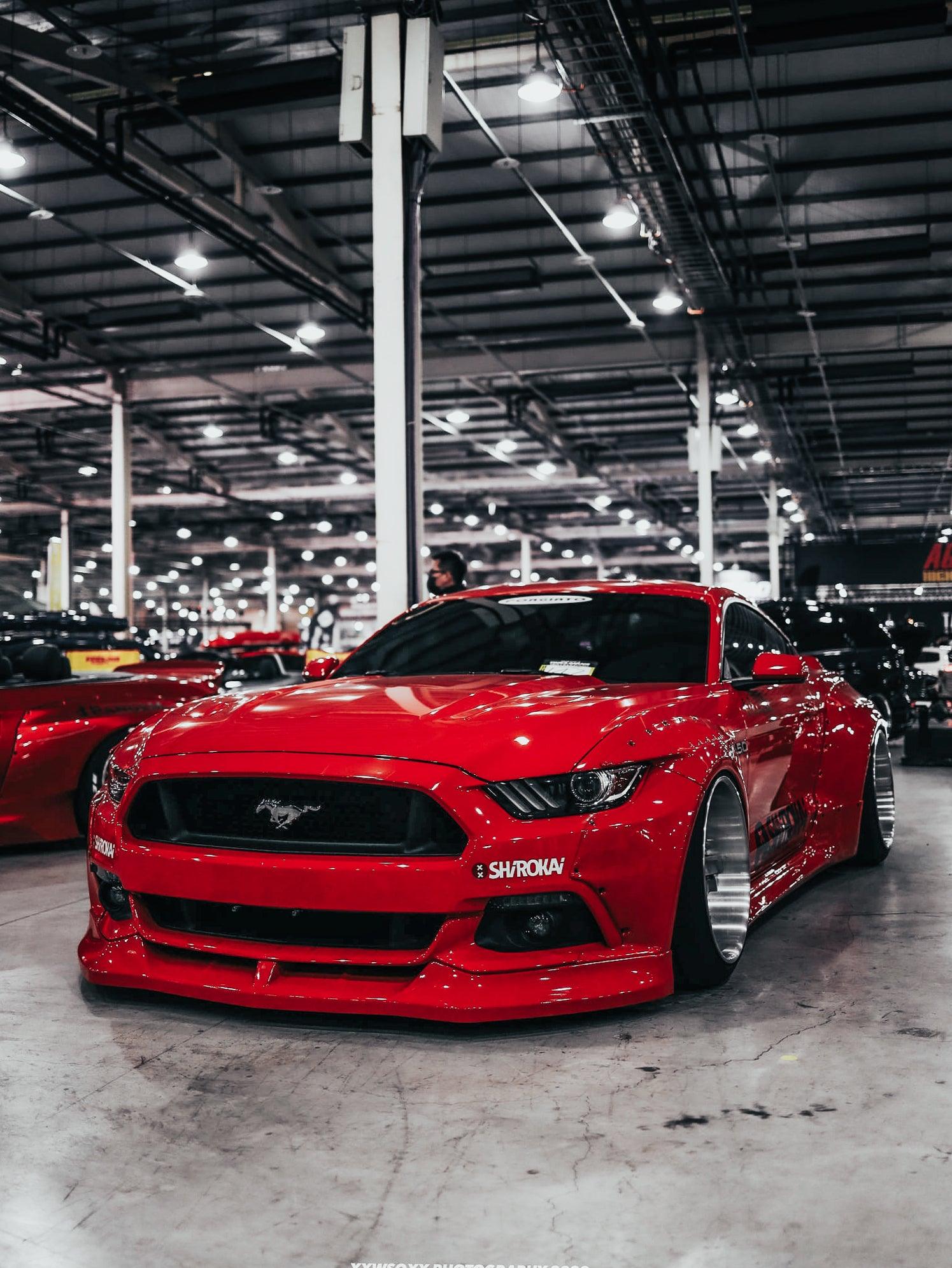 Red Ford Mustang S550 widebody kit SHIROKAI installed on a car in an indoor showroom