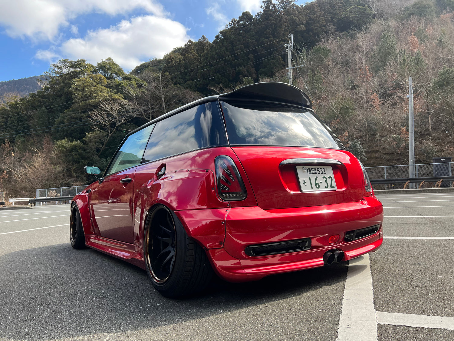 Red Mini Cooper S R53 with widebody kit SHIROKAI installed parked outdoors with black wheels